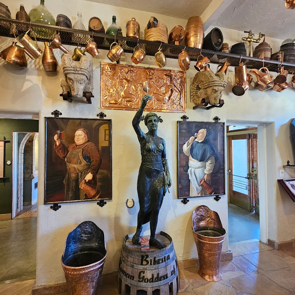 Vintage brewery-themed room with statues, copper tools, and historical artwork.