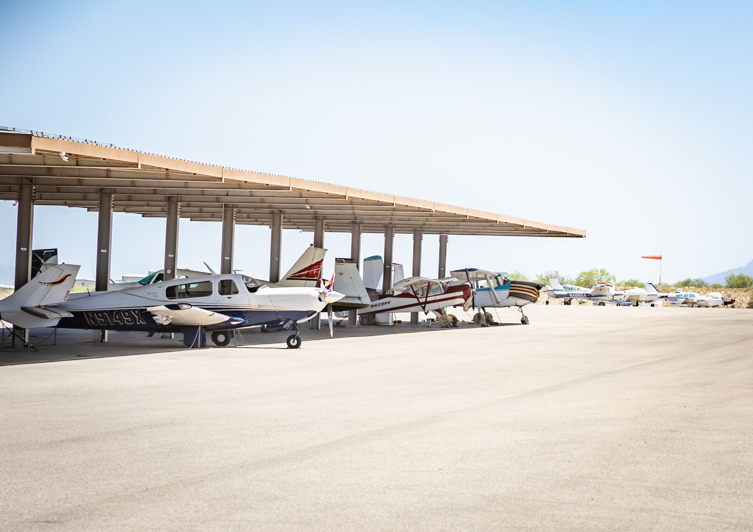 Small aircraft parked under shelter at an airport tarmac