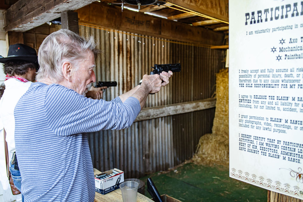 Elderly man participating in indoor pistol shooting range activity with safety waiver.