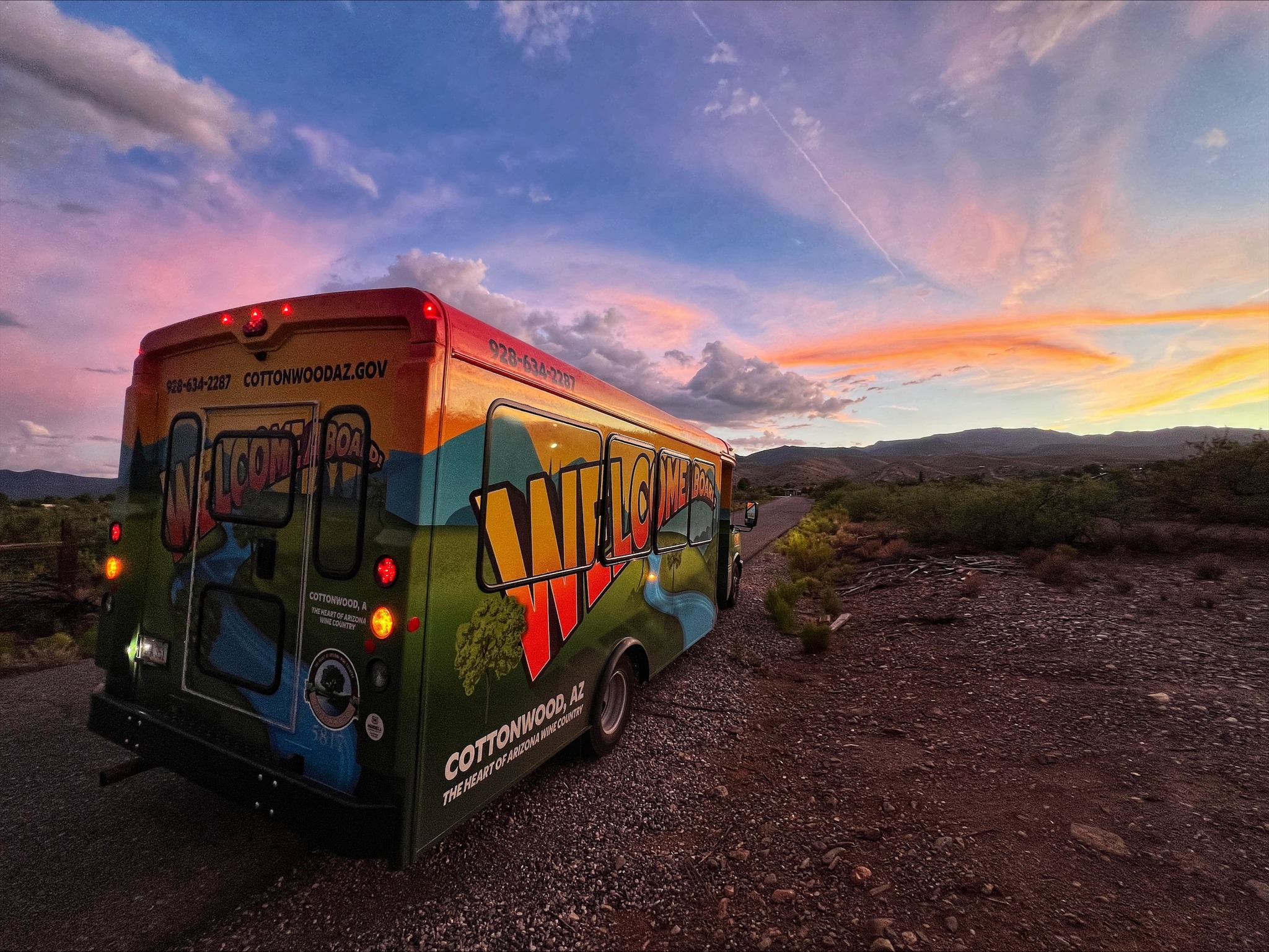 Colorful welcome bus in Cottonwood, AZ, during sunset on a scenic desert road.