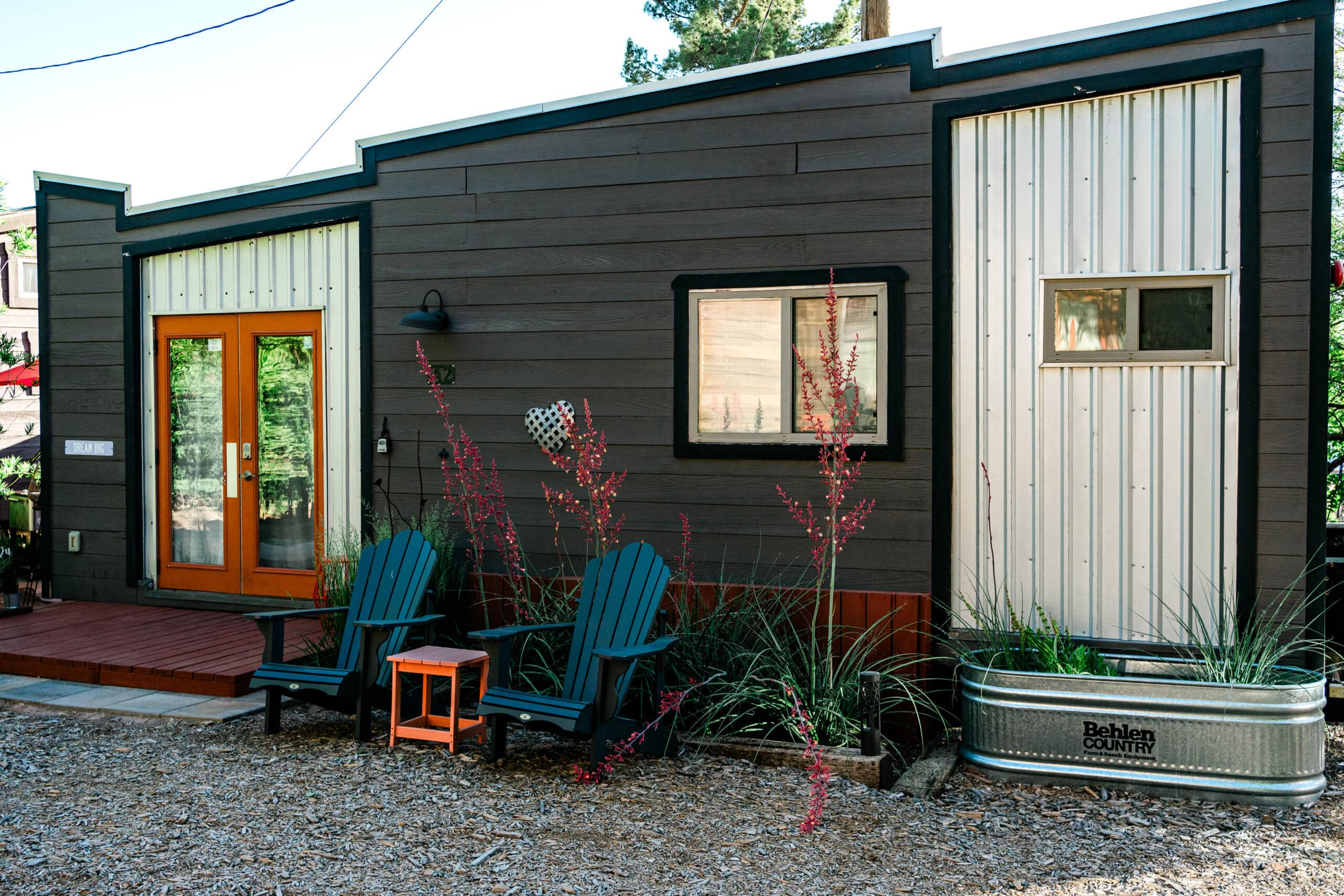 Cozy small modern home with Adirondack chairs, planters, and rustic decor