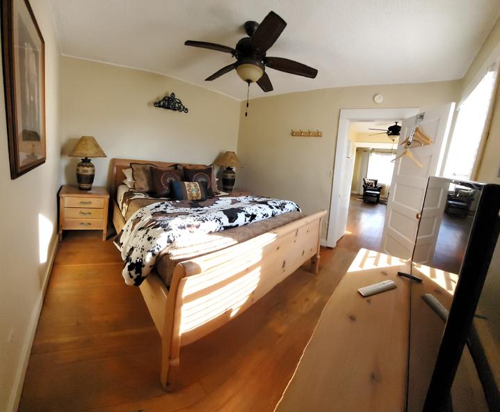 Cozy bedroom with hardwood floors, wooden bed, and open doorway to hallway.