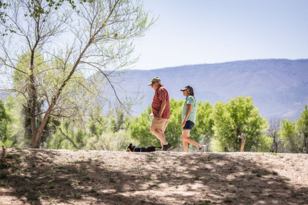 Two people hiking on a scenic trail with a dog resting nearby