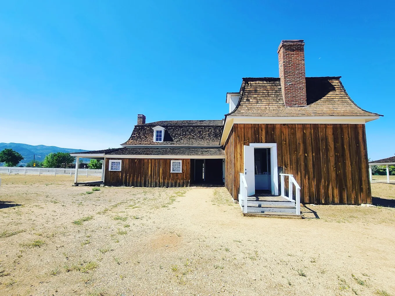 Historic wooden cabin with porch, clear blue sky, dry grass field
