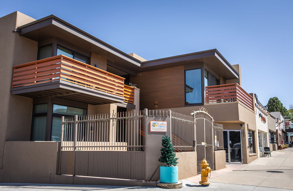 Modern two-story home with wooden balcony and metal gate, labeled Lofis Innovative Realty.