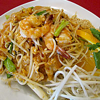 Delicious shrimp pad thai with rice noodles and fresh veggies on white plate