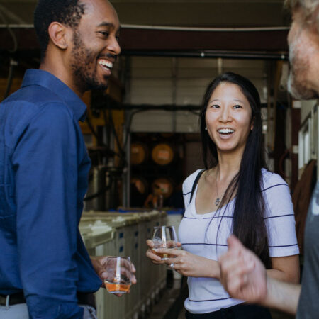 Three people laughing together at a brewery tasting event.