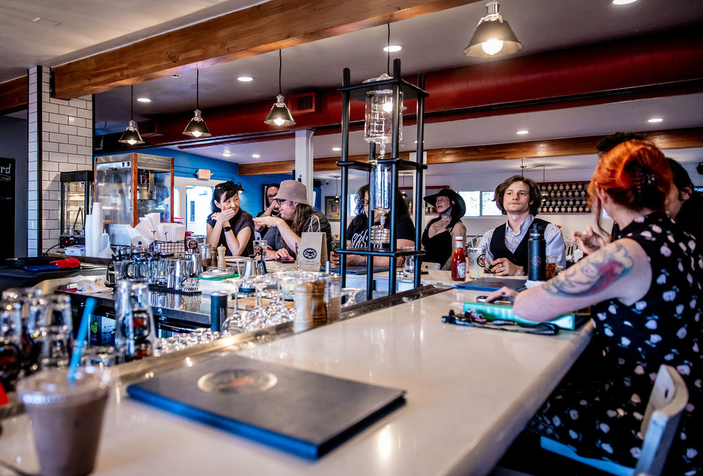 Group enjoying drinks at a modern bar counter with beverages and diverse patrons.