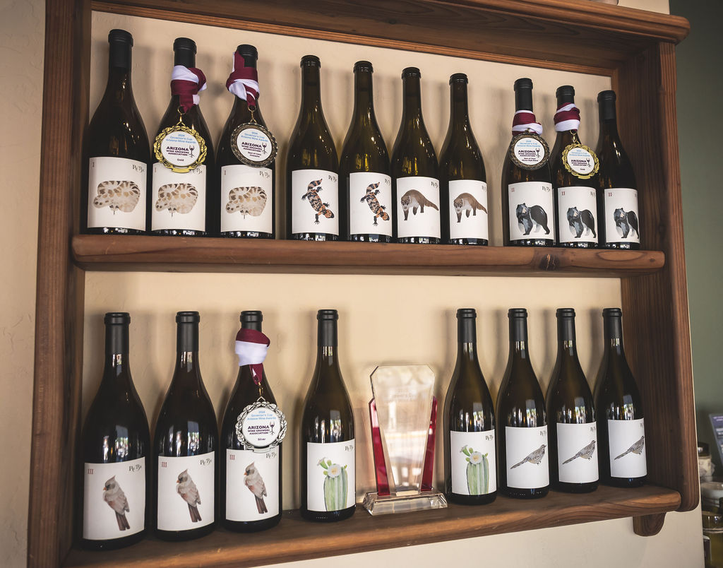 Two-tiered wine shelf displaying award-winning bottles with bird and cactus labels