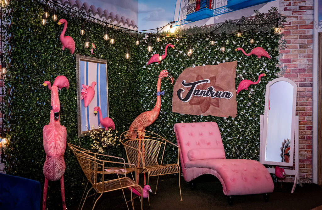 Whimsical flamingo-themed lounge with pink seating, string lights, and decorative elements.