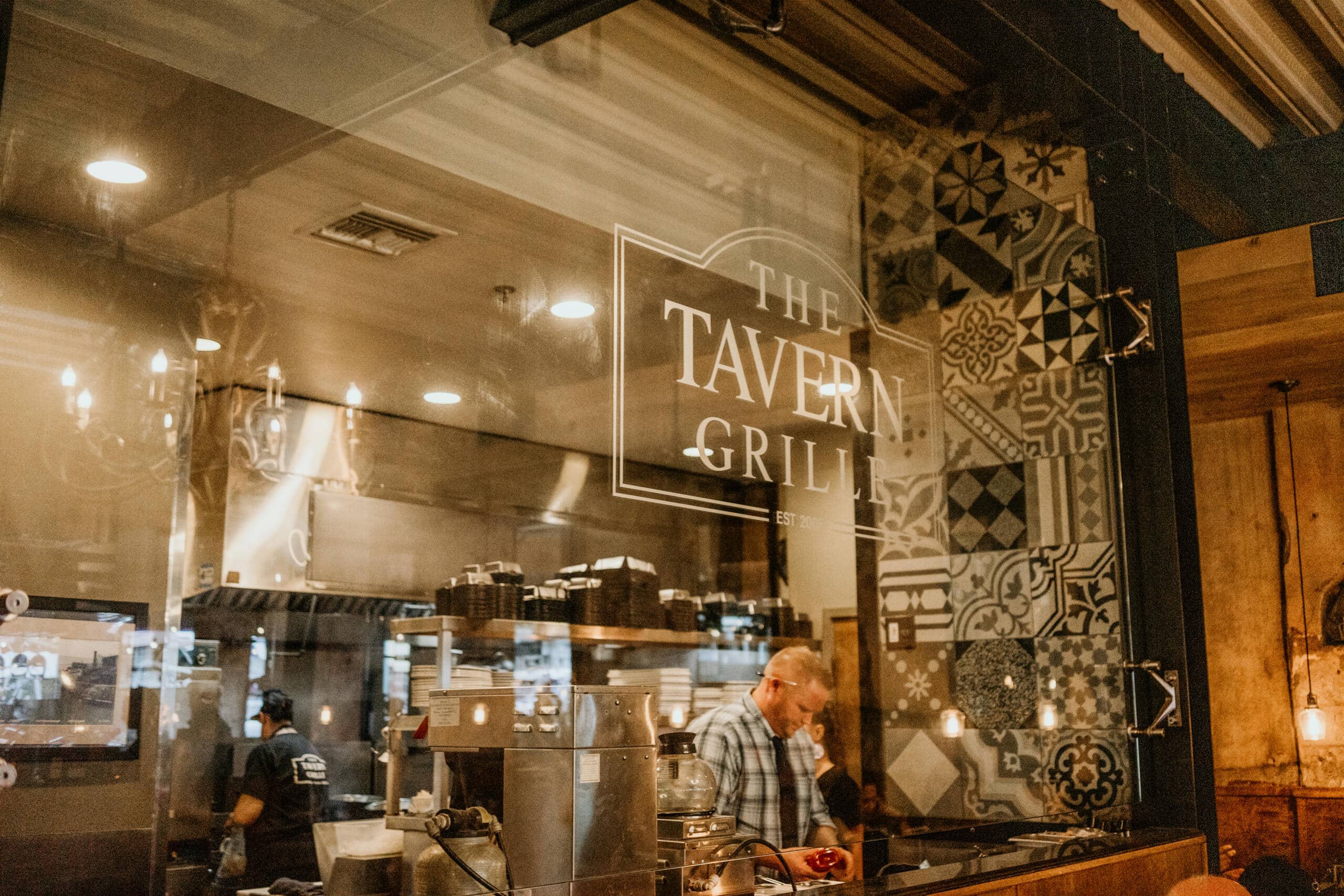 Cozy tavern grill interior with staff preparing food at a busy restaurant kitchen counter.