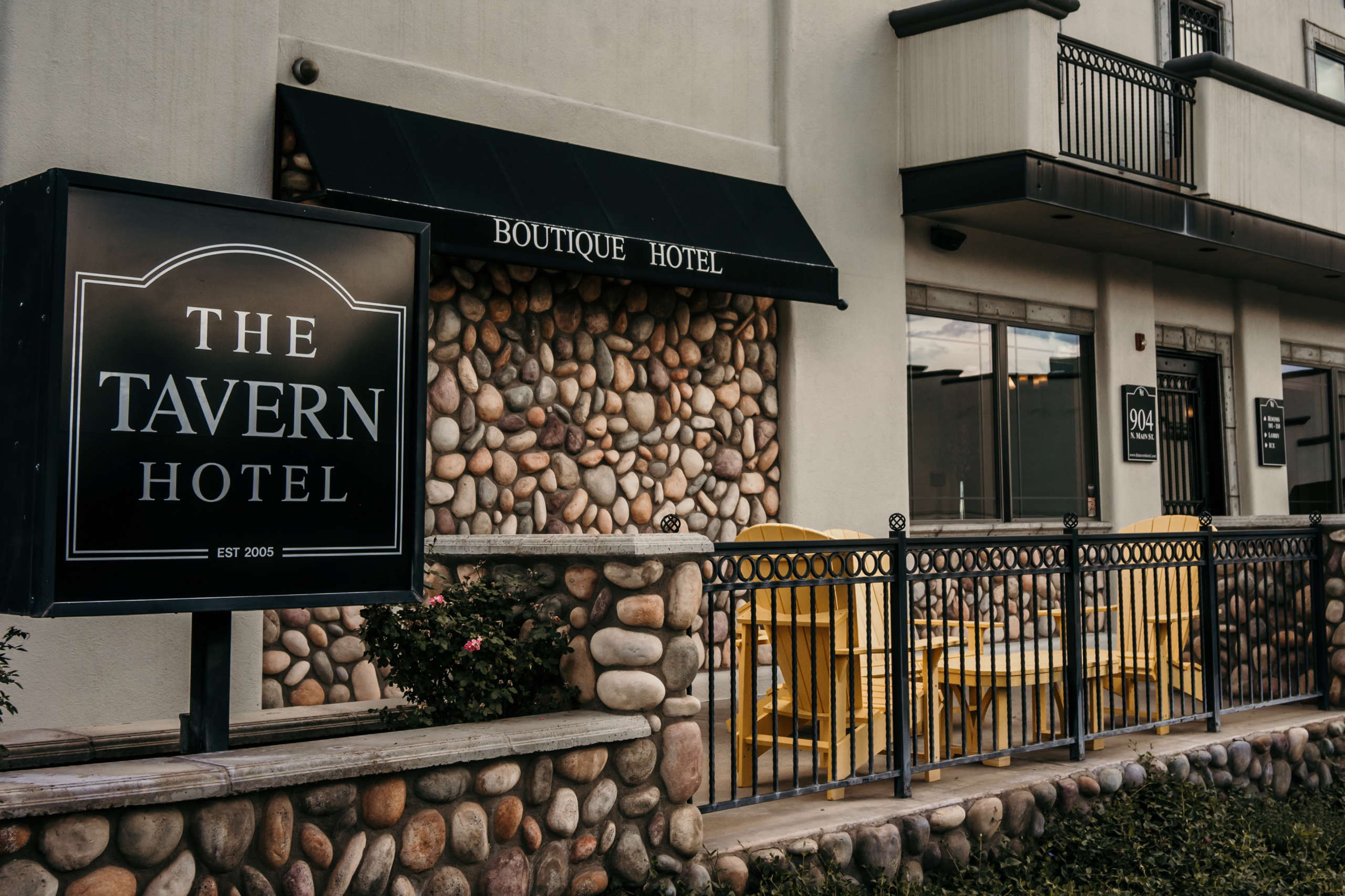 Boutique hotel exterior with rustic stone wall and sign reading The Tavern Hotel, est. 2005.