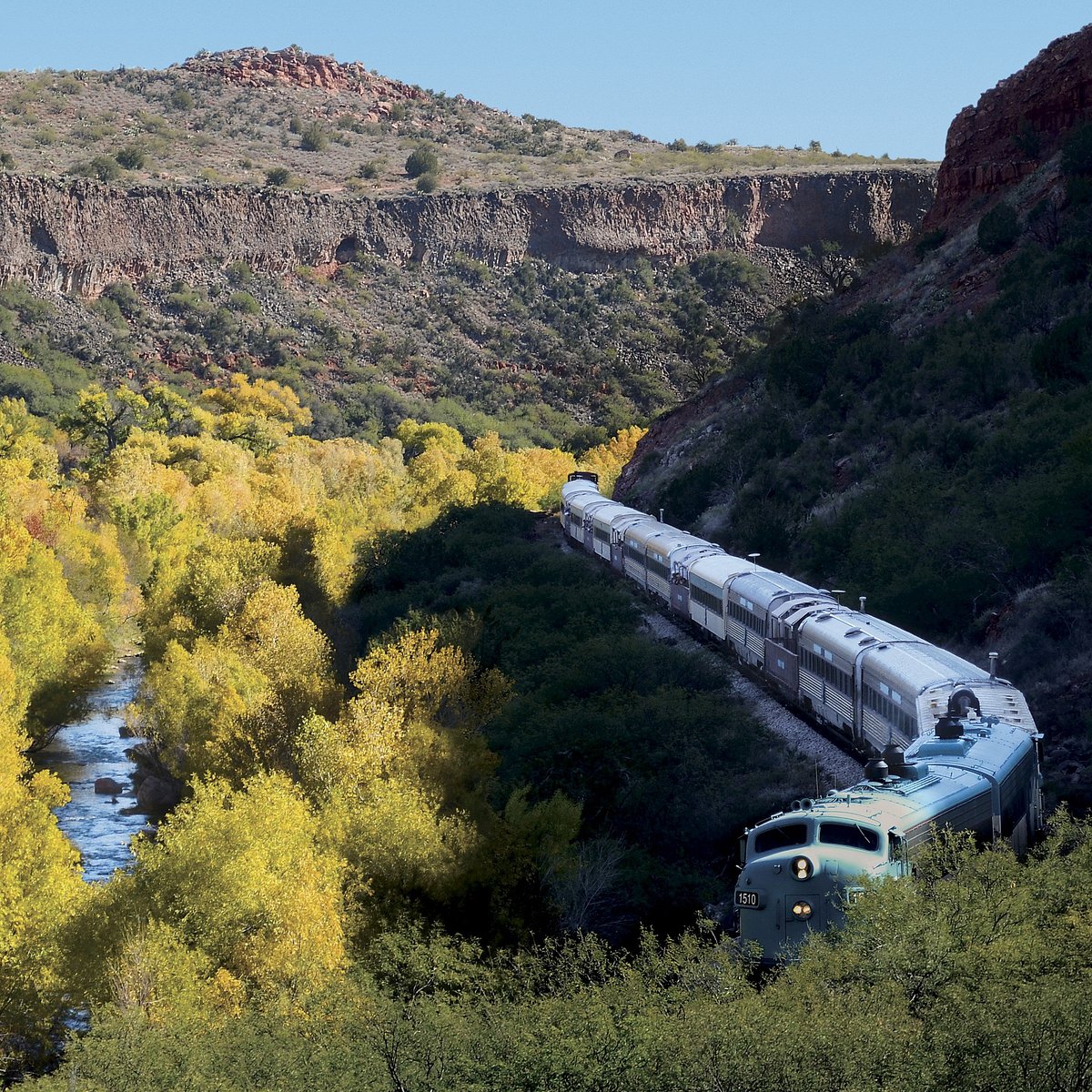 Vintage passenger train traveling through scenic autumn canyon landscape