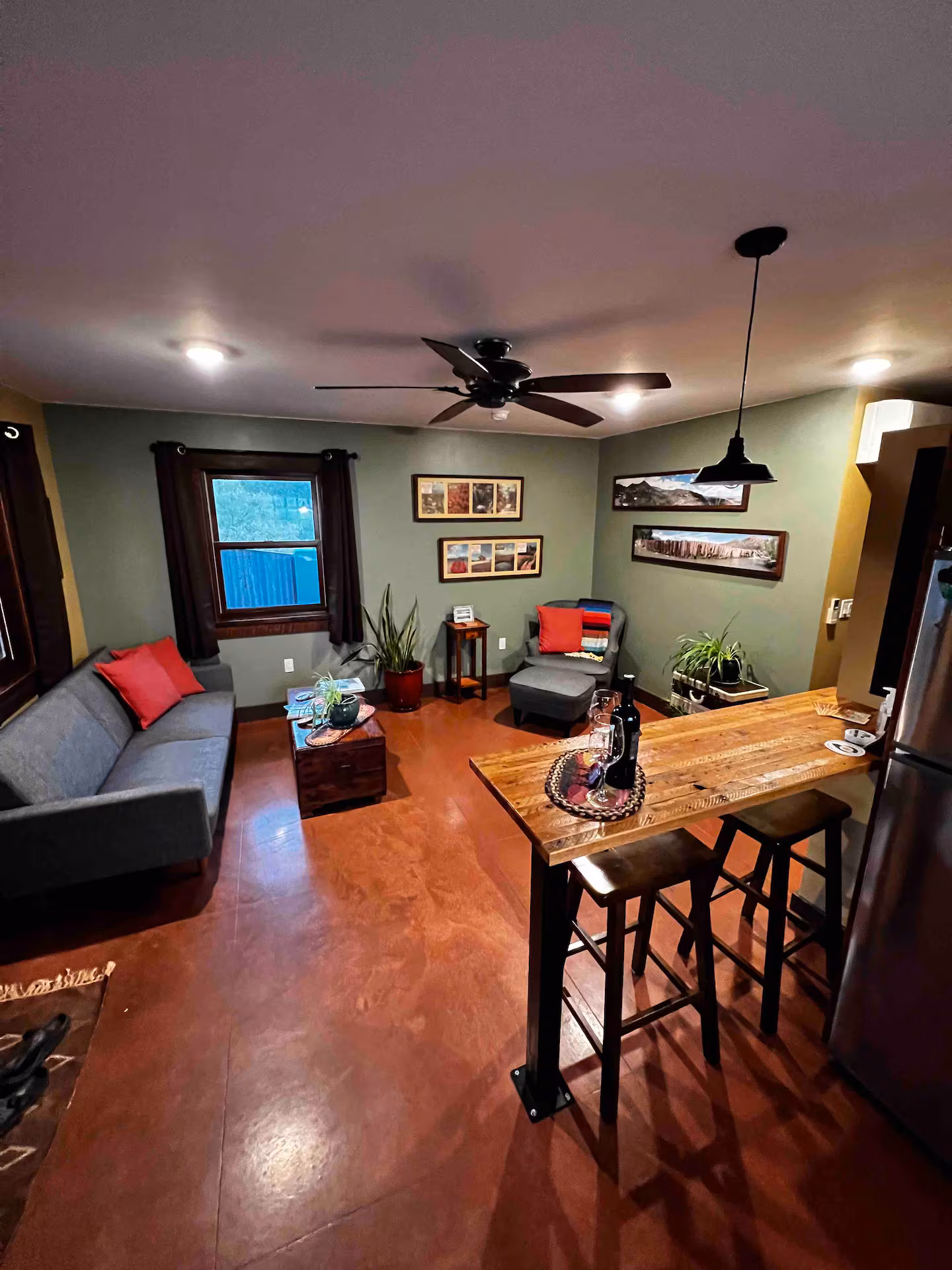 Cozy living room with bar, plants, and rustic decor.