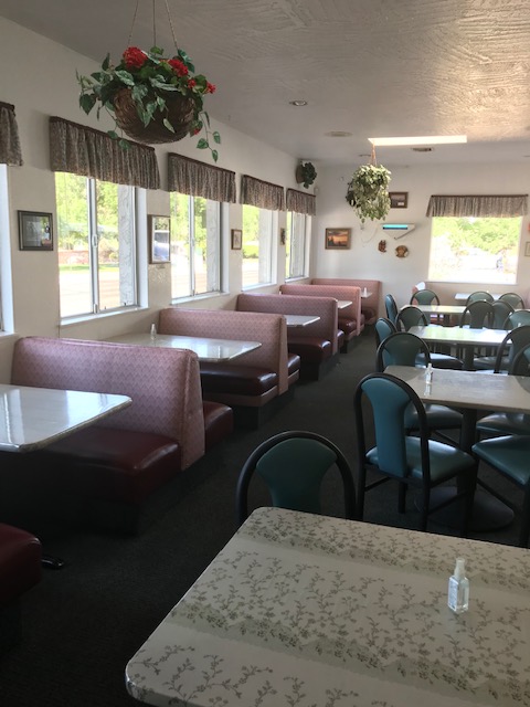 Cozy diner with booth seating, tables, and natural light near windows.