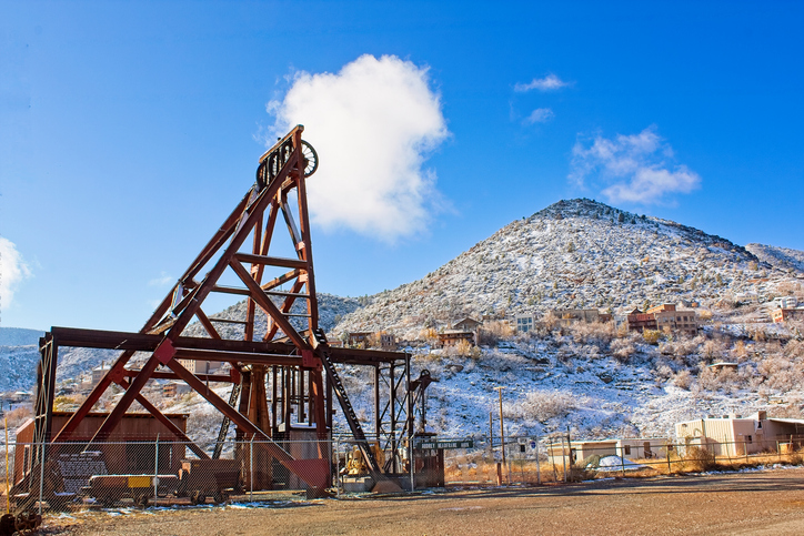 Abandoned mining hoist in snowy mountainous terrain under clear blue sky