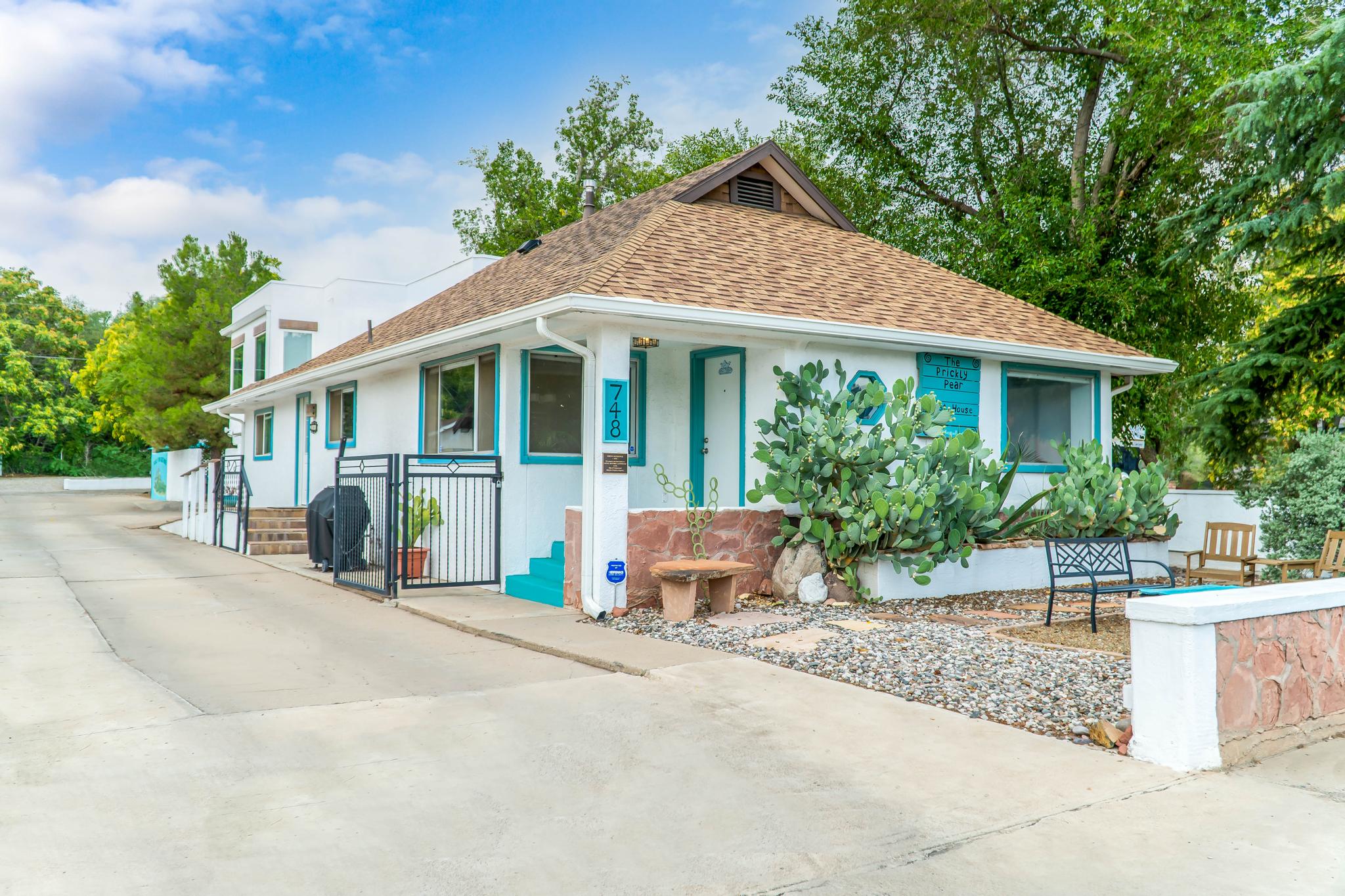 Charming small house with turquoise trim and desert plants near sidewalk