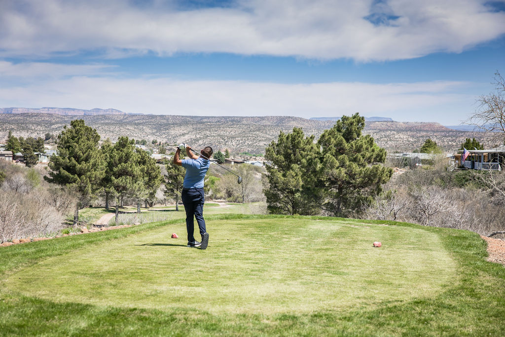 Golfer taking swing on scenic hilltop golf course with mountain views