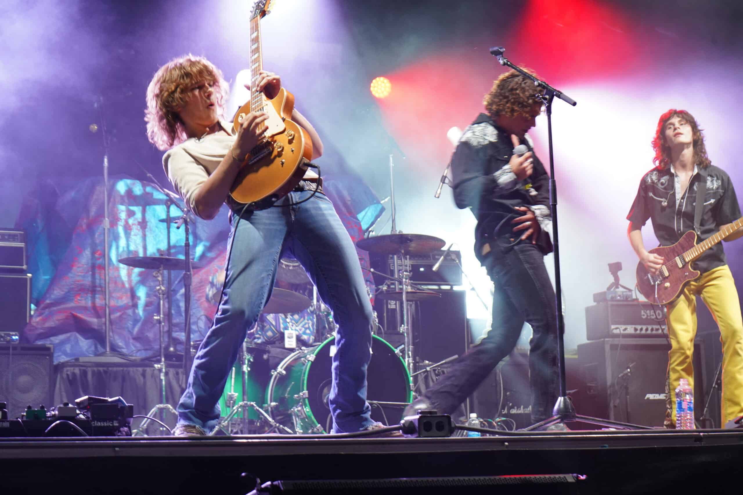 Band performing live with guitars and drum set on stage
