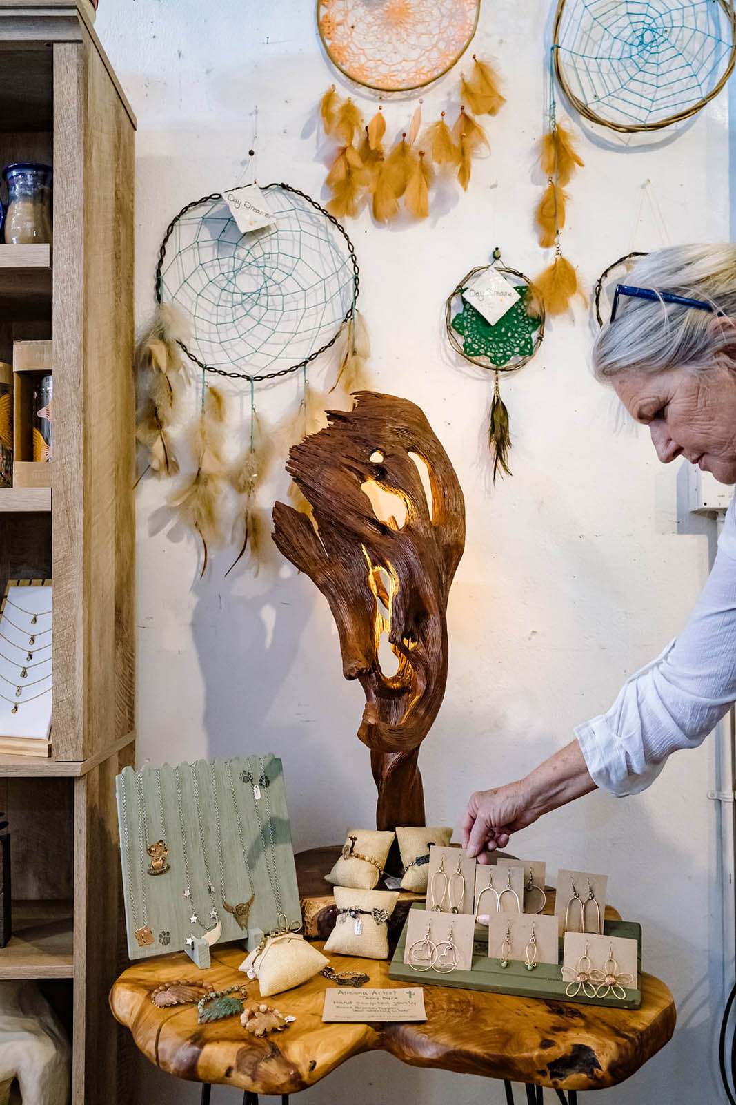 Artisan crafting handmade jewelry and dreamcatchers in a rustic boutique setting.