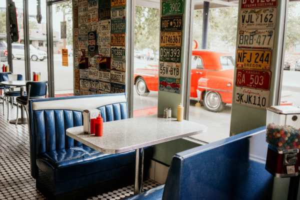 Vintage diner booth with license plate wall display and classic car outside