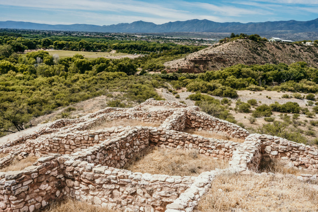 Ancient stone ruins overlooking green valley and distant mountains.