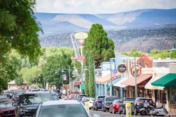 Small-town main street with shops, cars, mountains in background