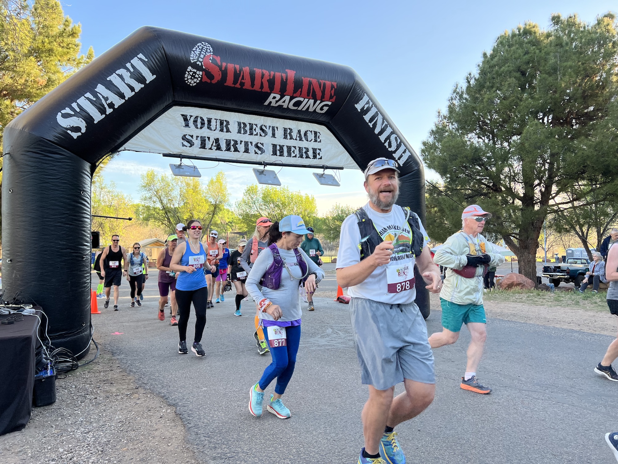 Runners at start line of Startline Finishing racing event, crossing beneath arch.