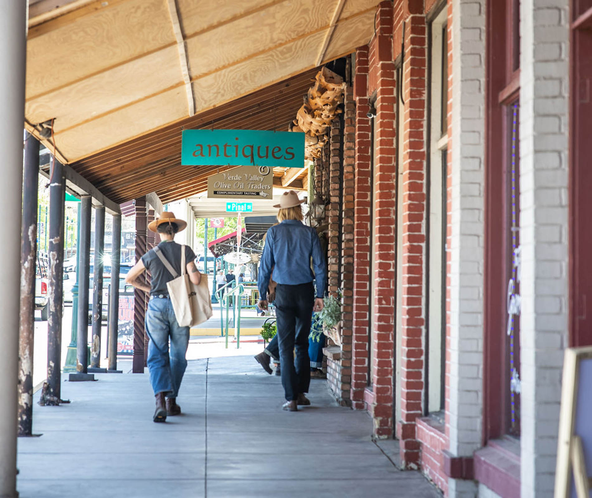 Two people walking past an antique shop in a charming covered shopping area.