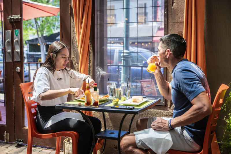 Two people eating outside at a café on a sunny day
