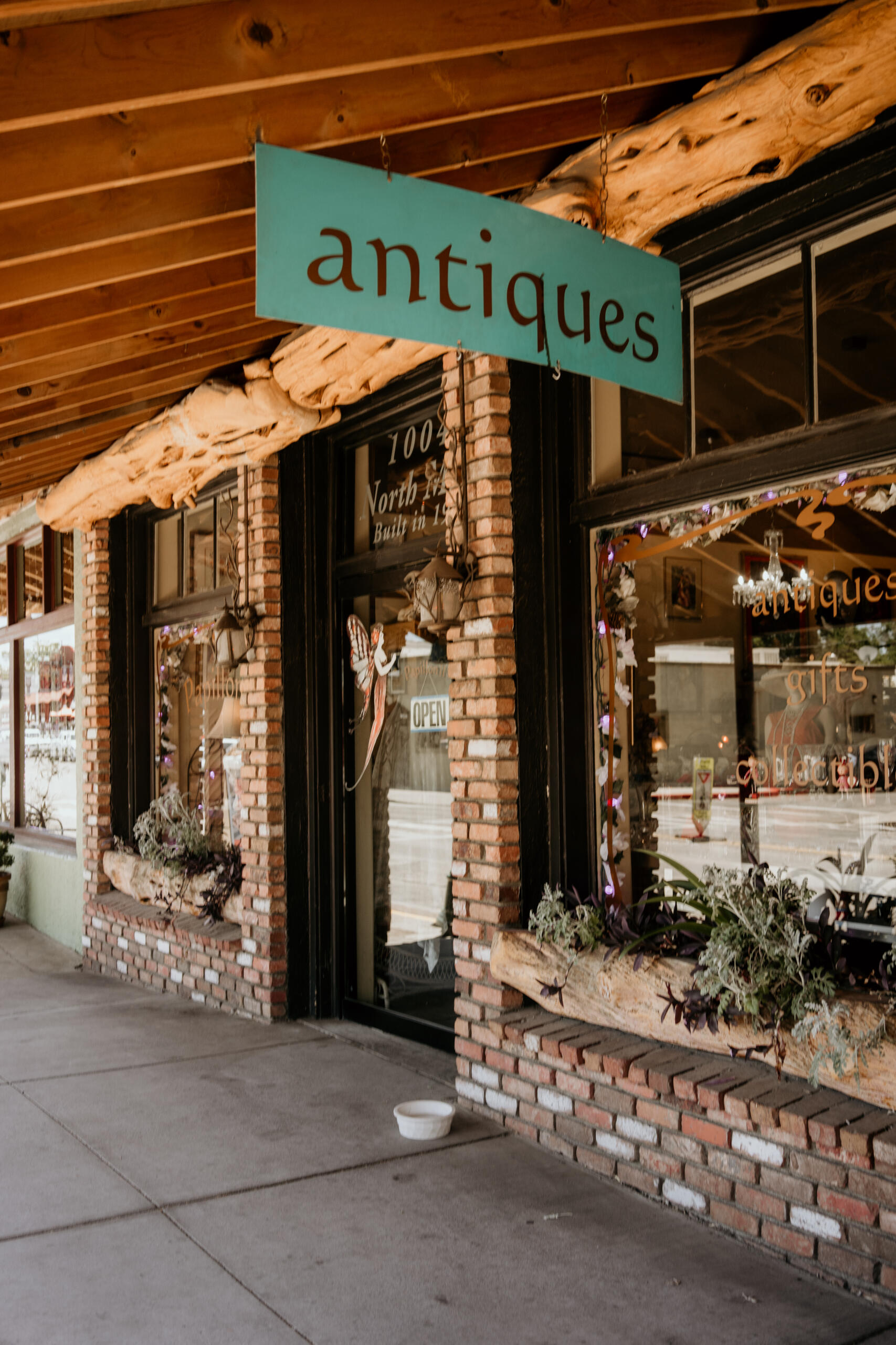 Charming antique shop front with rustic wooden and brick decor, open sign visible.