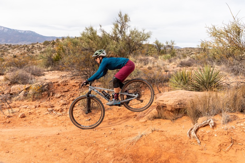 Mountain biker navigating rocky desert trail with rugged terrain background