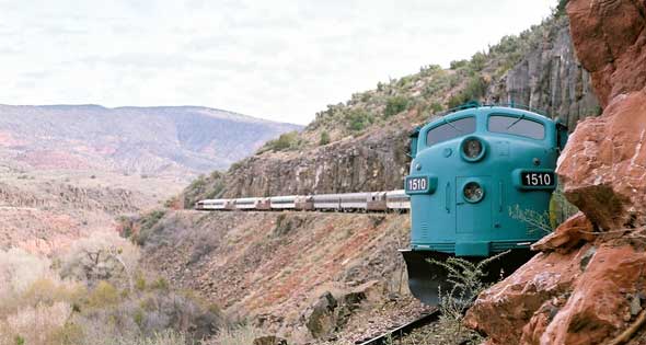 Blue train on curved track in desert landscape