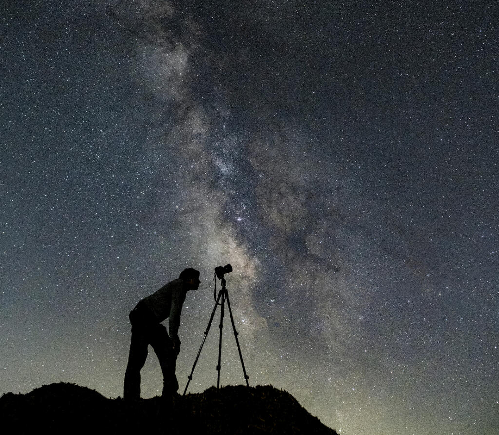 Silhouette of photographer capturing the Milky Way at night.