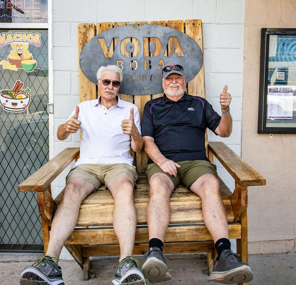 Two seniors pose with ice cream shop sign