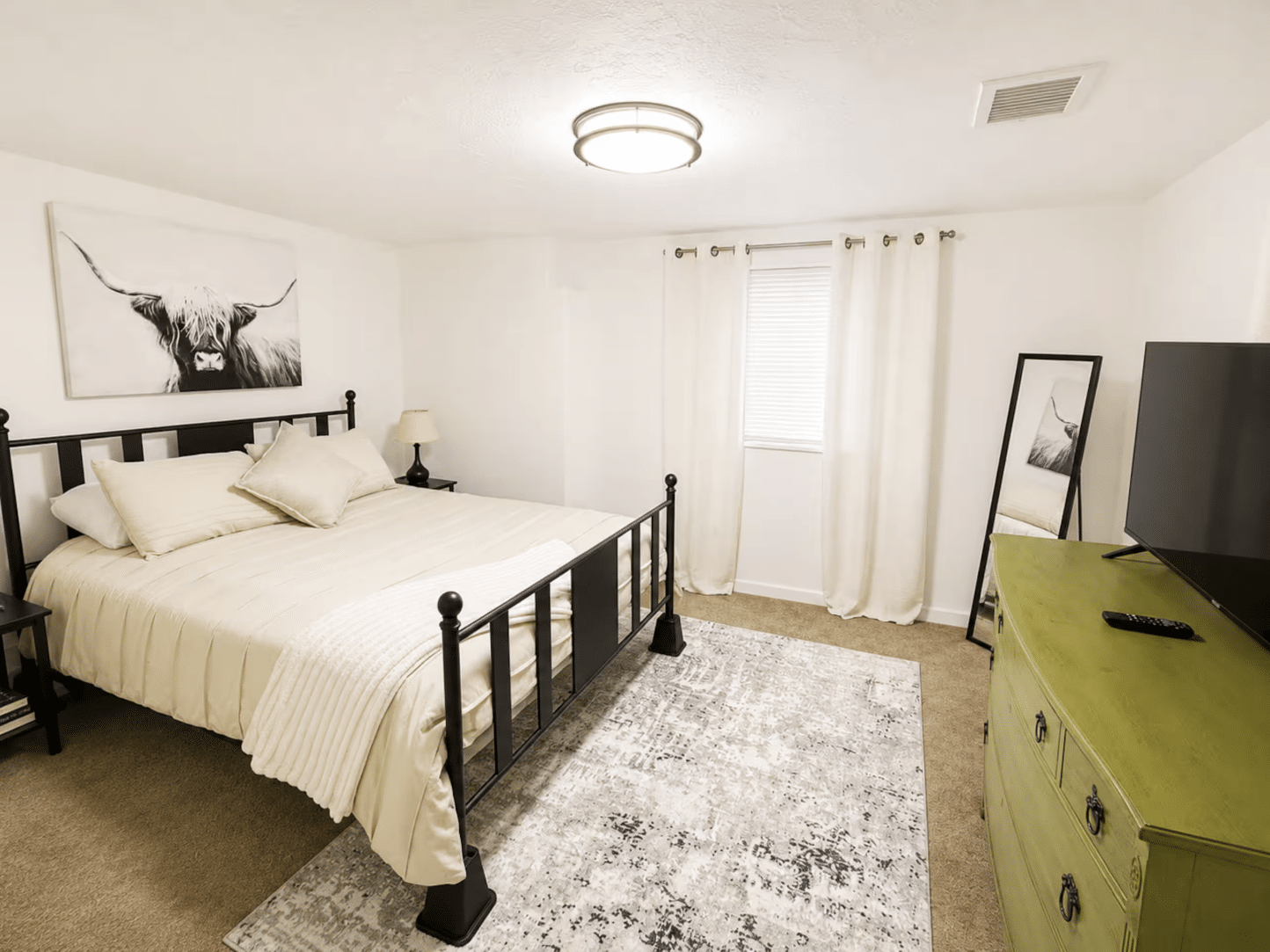 Bright bedroom with black metal bed and green dresser