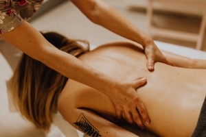 Therapist giving a back massage to a person lying on a massage table
