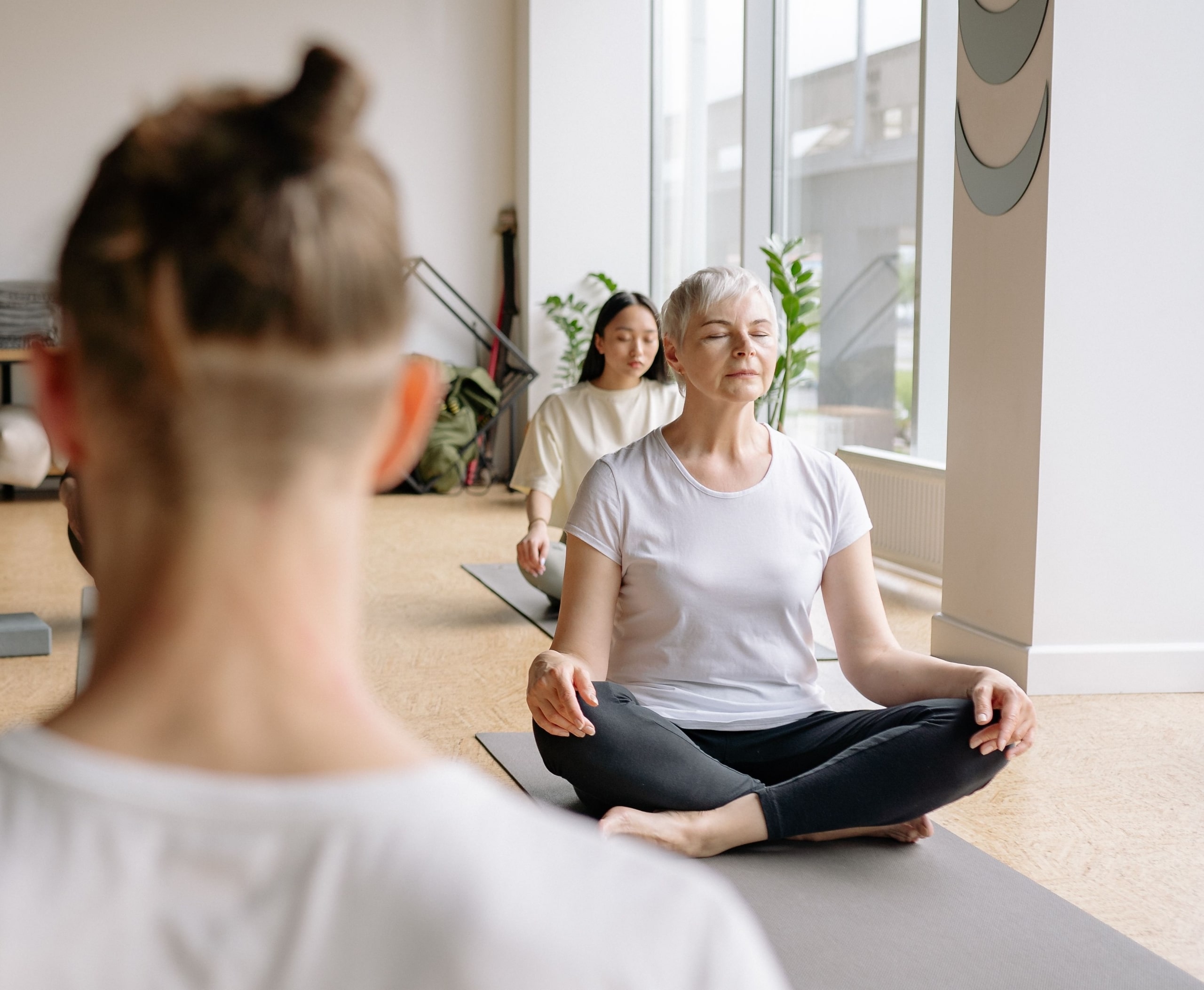 pexels-yankrukov-8436726 (1) Three women meditate together in a bright yoga studio.