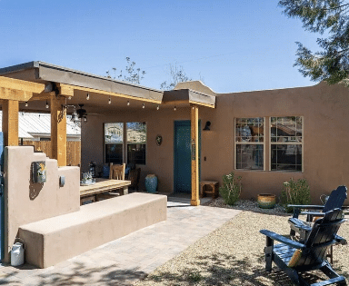 Southwestern stucco patio with pergola, blue door, and chairs
