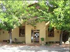 Tree-shaded entrance of a beige stucco building