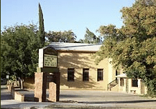 Historic stone house with sign and surrounding trees
