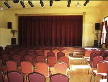 Empty auditorium with red seats and closed stage curtain